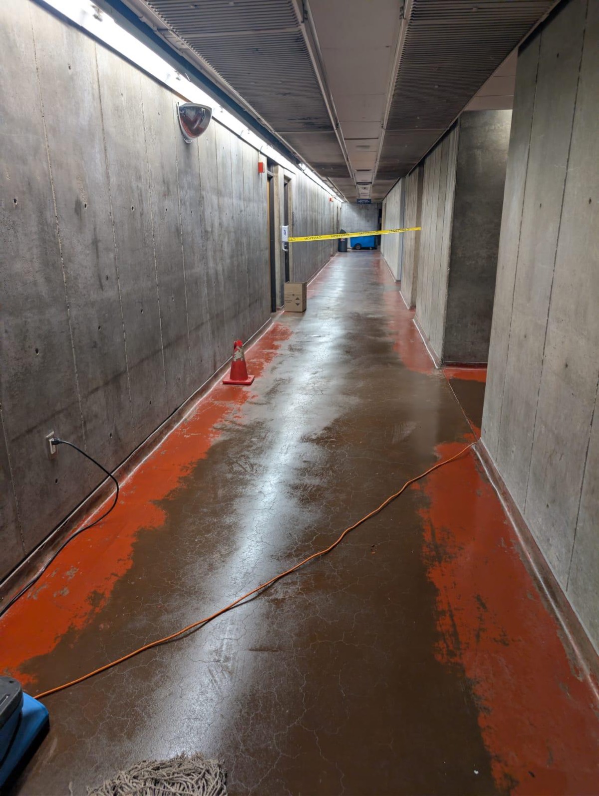 Extraction hose running down an underground parking corridor with water across the floor