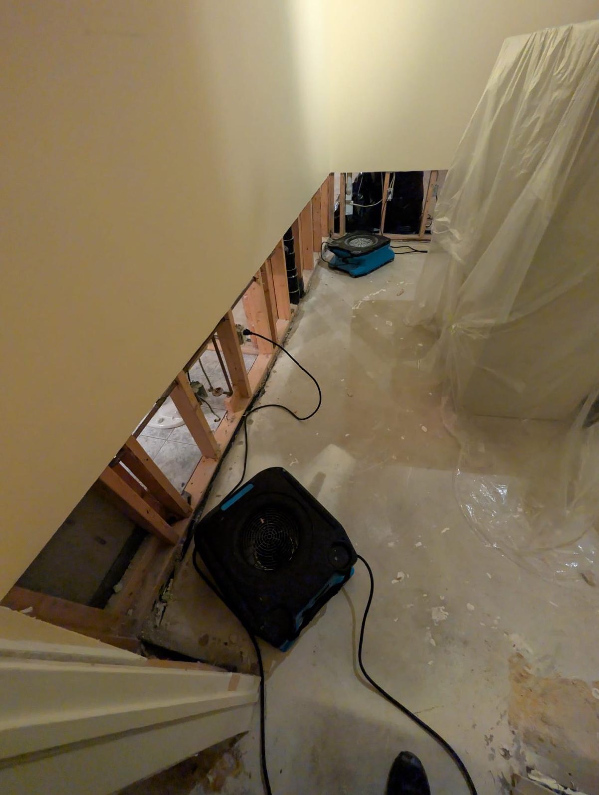 Air mover drying a hallway with the contents covered in plastic sheeting