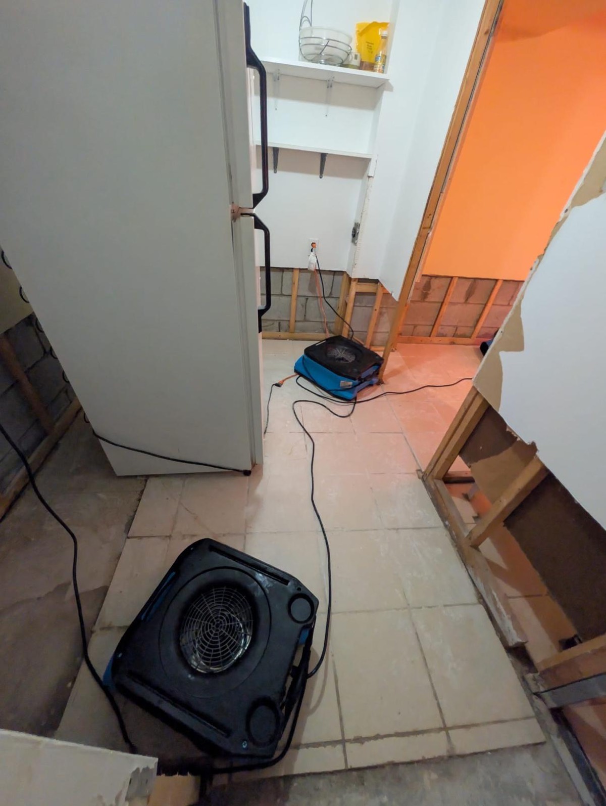 Air movers drying a laundry area after the wet drywall was cut out