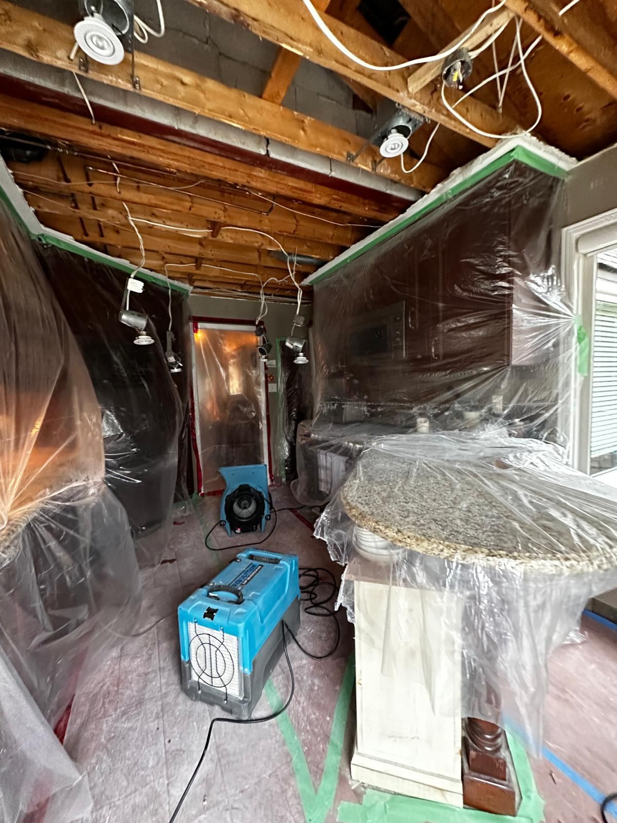 Plastic containment and a dehumidifier set up during mold and water damage work in a Toronto home