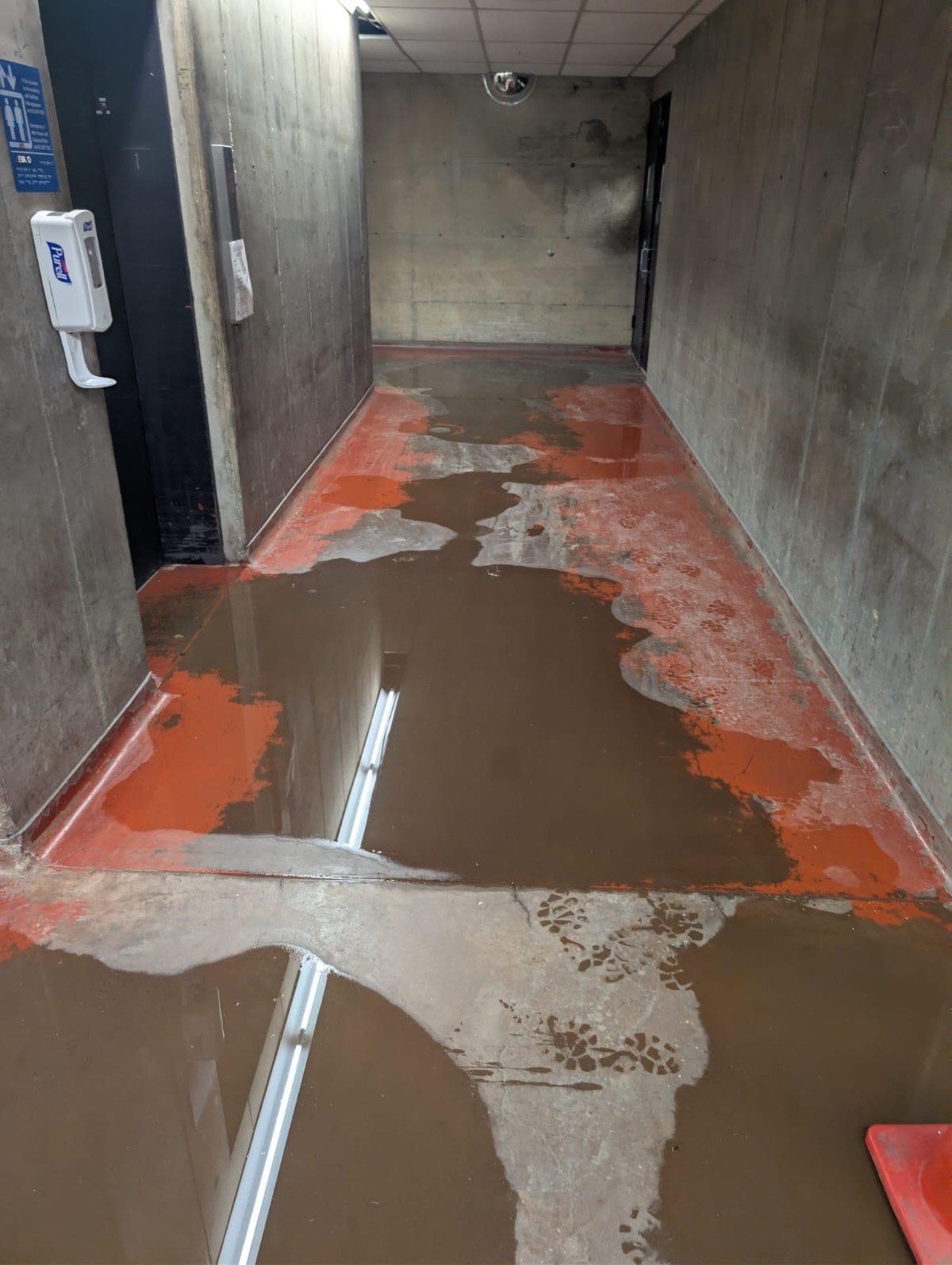Standing water pooled across a concrete commercial corridor floor