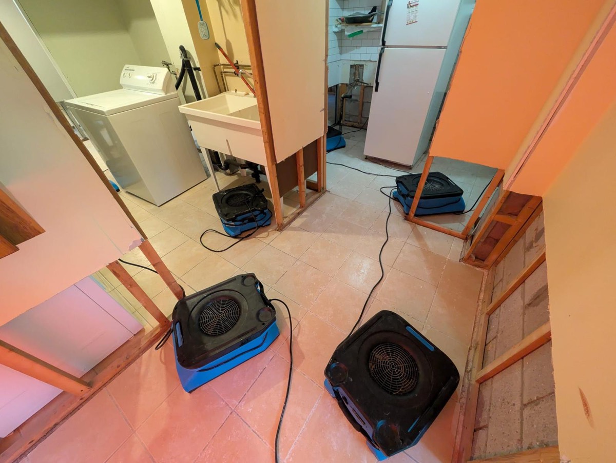 Four air movers drying a utility room after the wet drywall came out