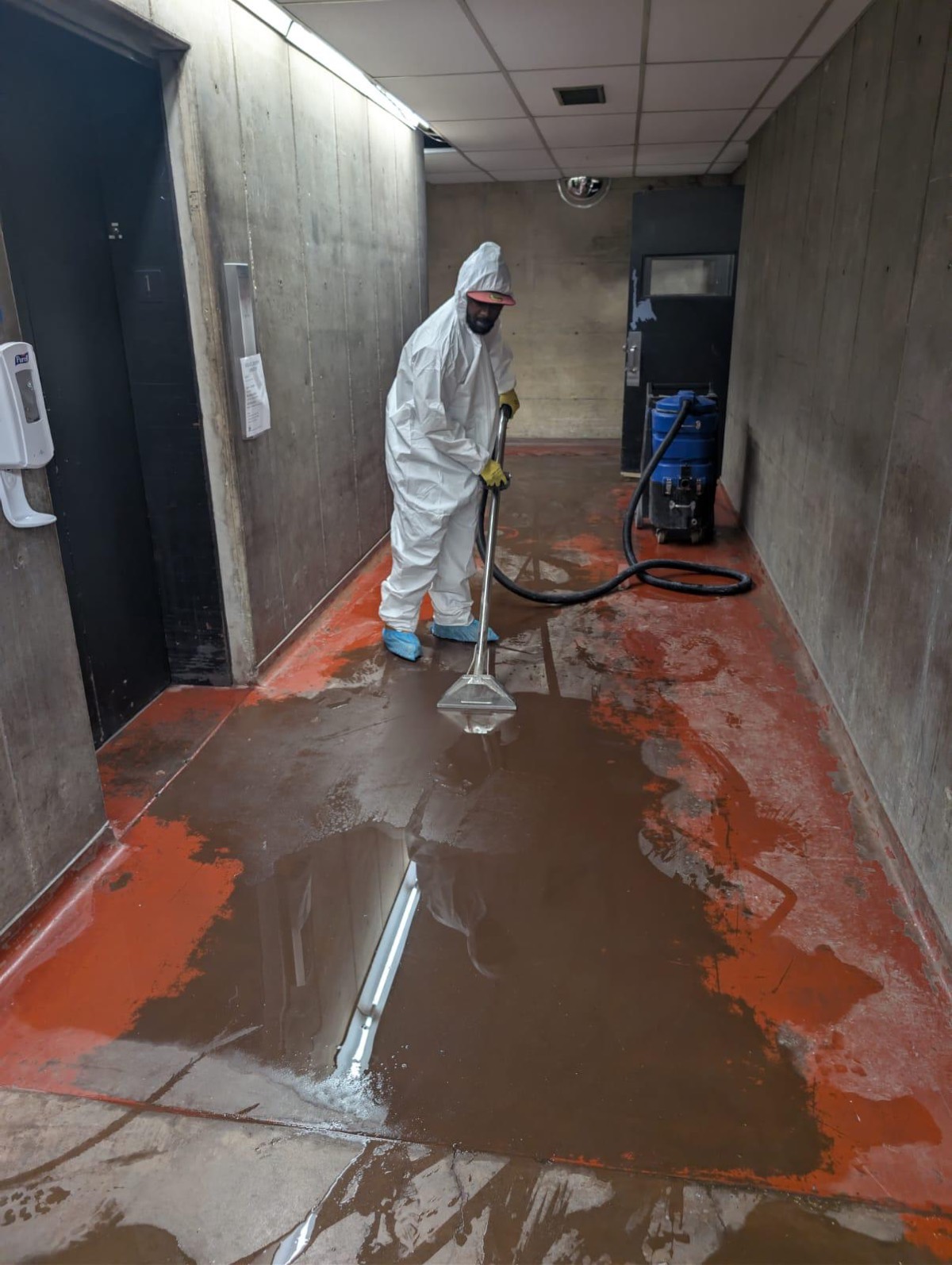 Technician extracting standing water from a commercial corridor floor